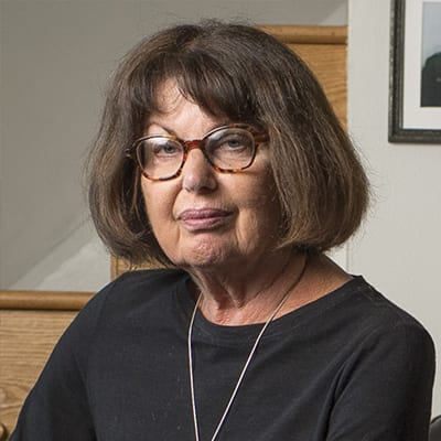 Elderly Caucasian American woman with a black shirt on and a silver necklace.