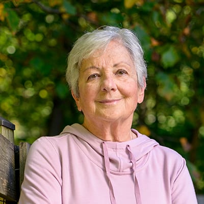 Middle aged Caucasian American women wearing a pink sweatshirt and smiling.